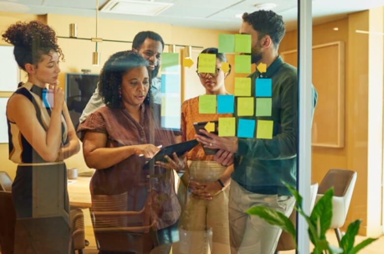 People communicating and using sticky notes on a glass wall